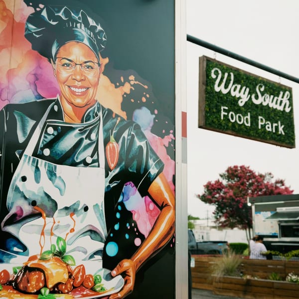 Colorful mural of a smiling chef holding two plates of food next to a "Way South Food Park" sign.