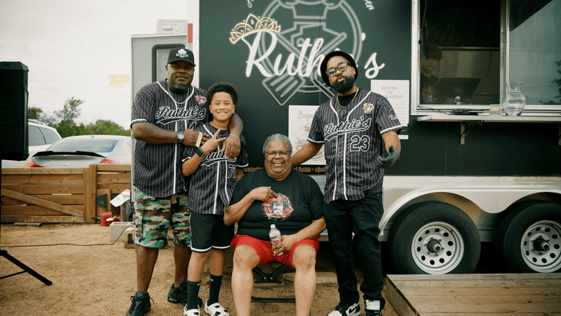 Four people, three men and one woman, pose in front of the Ruthie's food truck.